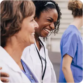 Two female doctors are laughing together in a hallway