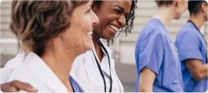 Two female doctors are laughing together in a hallway