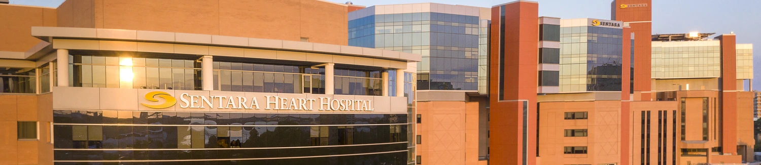 The exterior of Sentara Heart Hospital, a modern building with large windows reflecting the evening light.