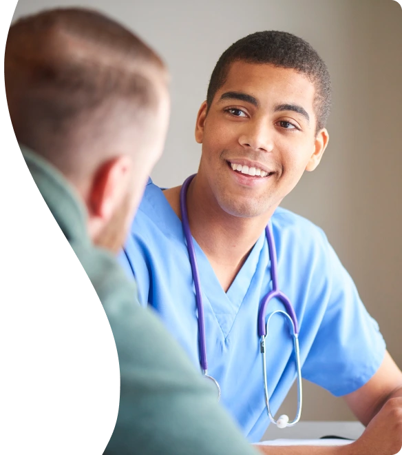 A doctor with a stethoscope around his neck smiles at a patient