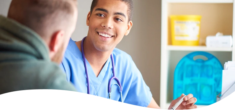 A doctor with a stethoscope around his neck smiles at a patient